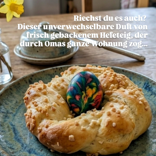 Foto eines goldbraun gebackenen, handgeflochtenen Osterkranzes aus Hefeteig mit einem bunt gefärbten Ei in der Mitte auf einem rustikalen Holztisch mit Frühlingsdekoration