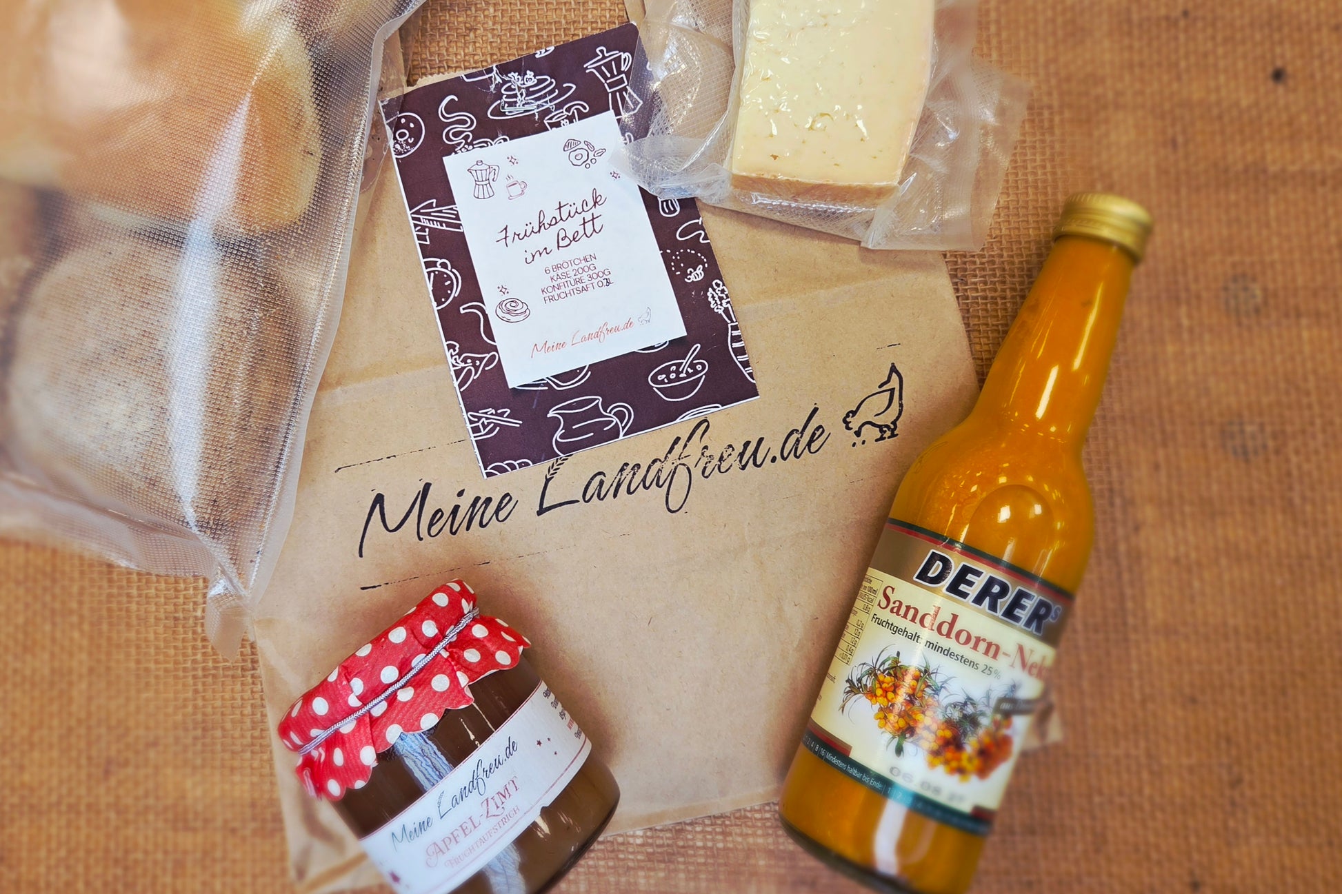 Romantisches Frühstück im Bett zum Valentinstag mit ofenfrischen Brötchen, Käse und Konfitüre aus der regionalen Frühstückstüte.